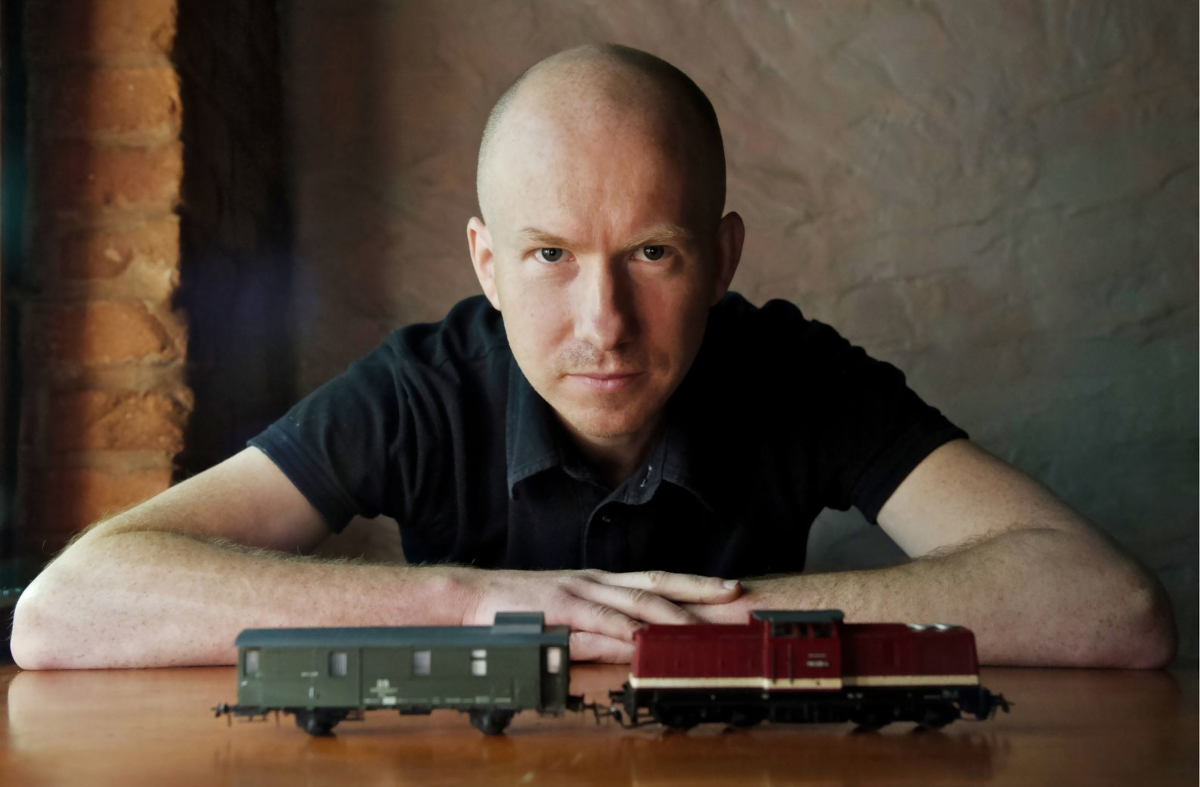 Autor Piotr Milewski przed nim figurka pociągu i wagonu