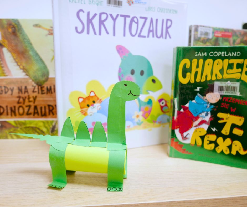 Zdjęcie pracy plastycznej dinozaura na tle książek.