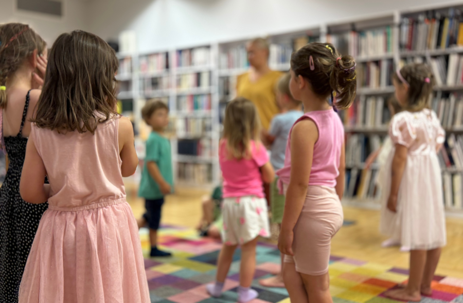 Grupa dzieci na kolorowym dywanie w bibliotece