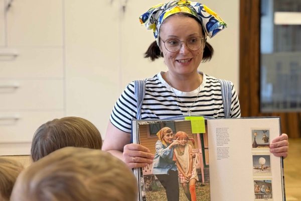 Zdjęcie prowadzącej z książką, w której zamieszczono zdjęcie Astrid Lindgren podczas kręcenia filmu o Pippi Pończoszance.