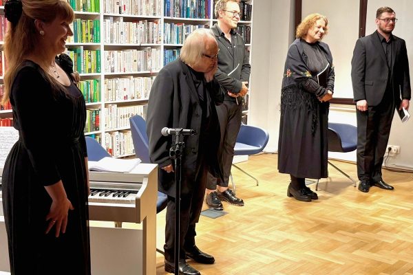 Aktorzy i pianistka stoją na scenie, uśmiechnięci, w tym czasie klaszcze publiczność niewidoczna na zdjęciu